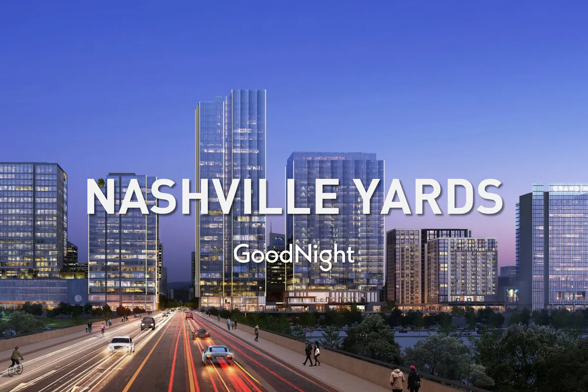 The photo captures tall glass buildings and a busy roadway illuminated by city lights, evoking the vibrant atmosphere of Nashville’s Midtown area. It encapsulates the energy of evening strolls, dining, and exploration after a productive workday.