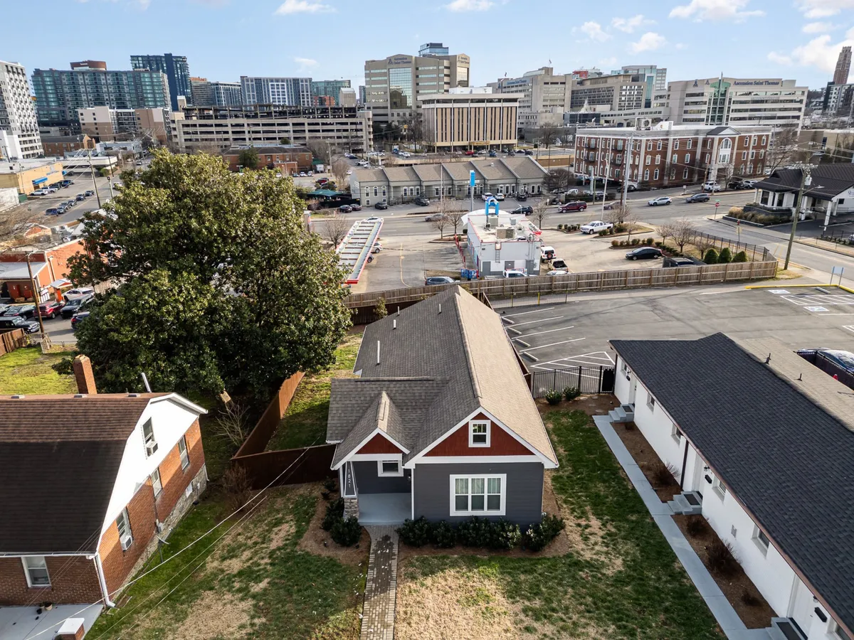 This image showcases a single-family house shaded by a large tree, with a view of the city skyline in the background. The inviting exterior hints at a tranquil, private space that is also closely connected to the urban environment—perfect for business travelers seeking convenience and relaxation.