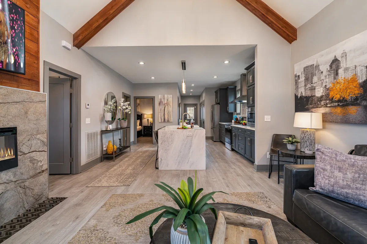 A stylish interior view of a modern kitchen island, cozy sitting area, and a glowing fireplace. The space is set for entertaining, with ample room for hosting meals, drinks, and evening gatherings in a comfortable, upscale setting.